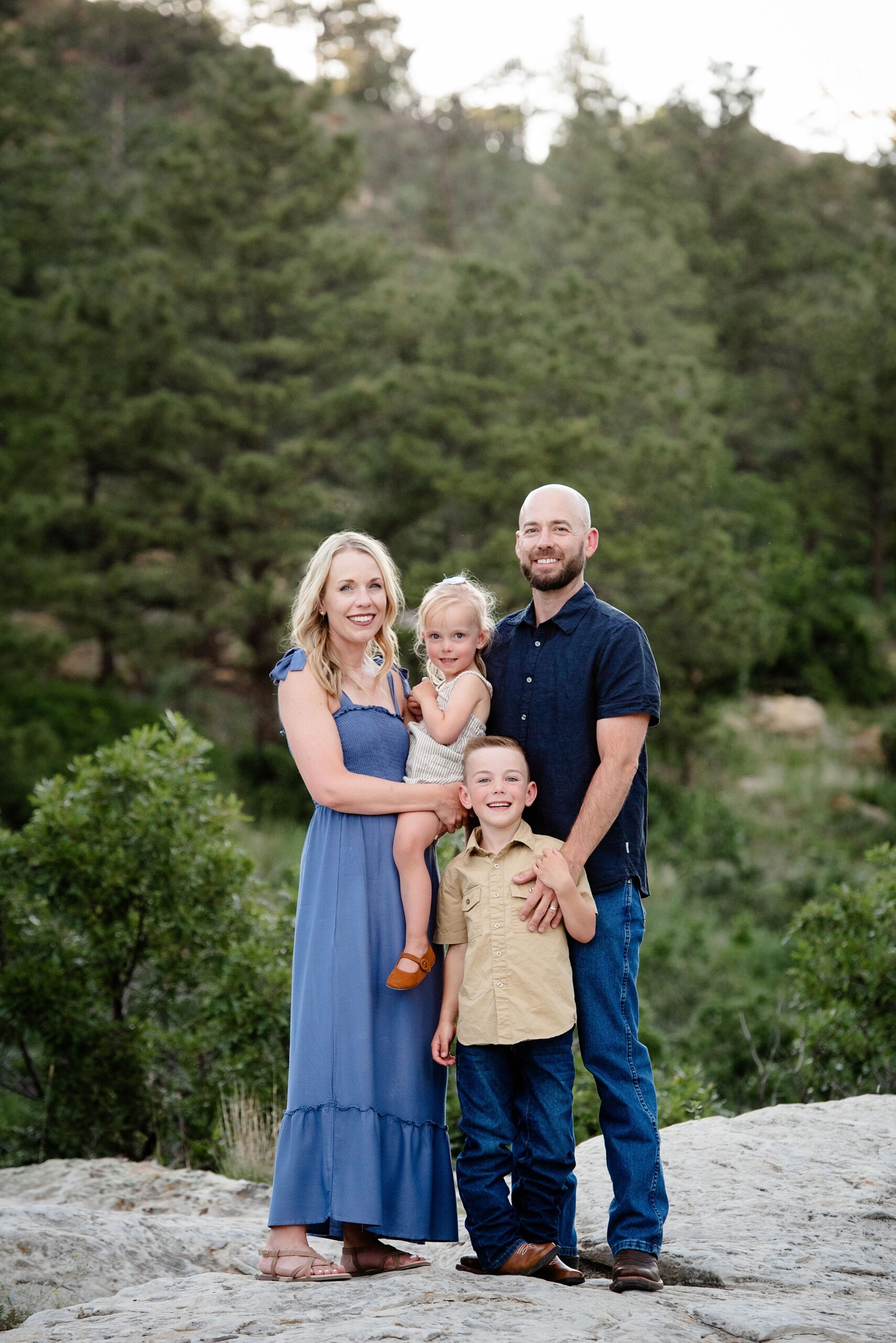 Happy parents stand with their two toddler children on a boulder smiling after visiting denver preschools