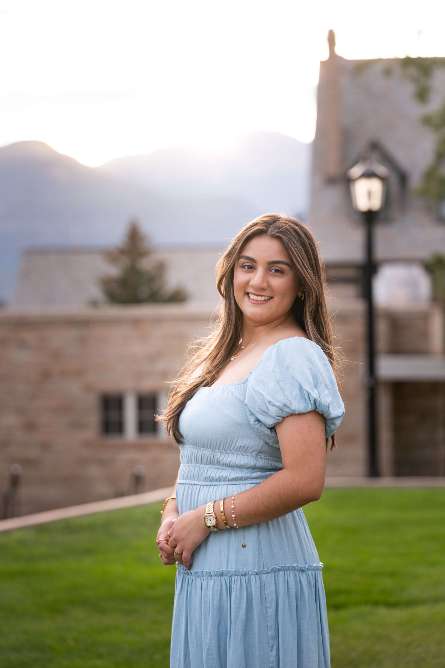 A high school senior stands at sunset smiling in a blue dress from one of the Colorado Springs Boutiques