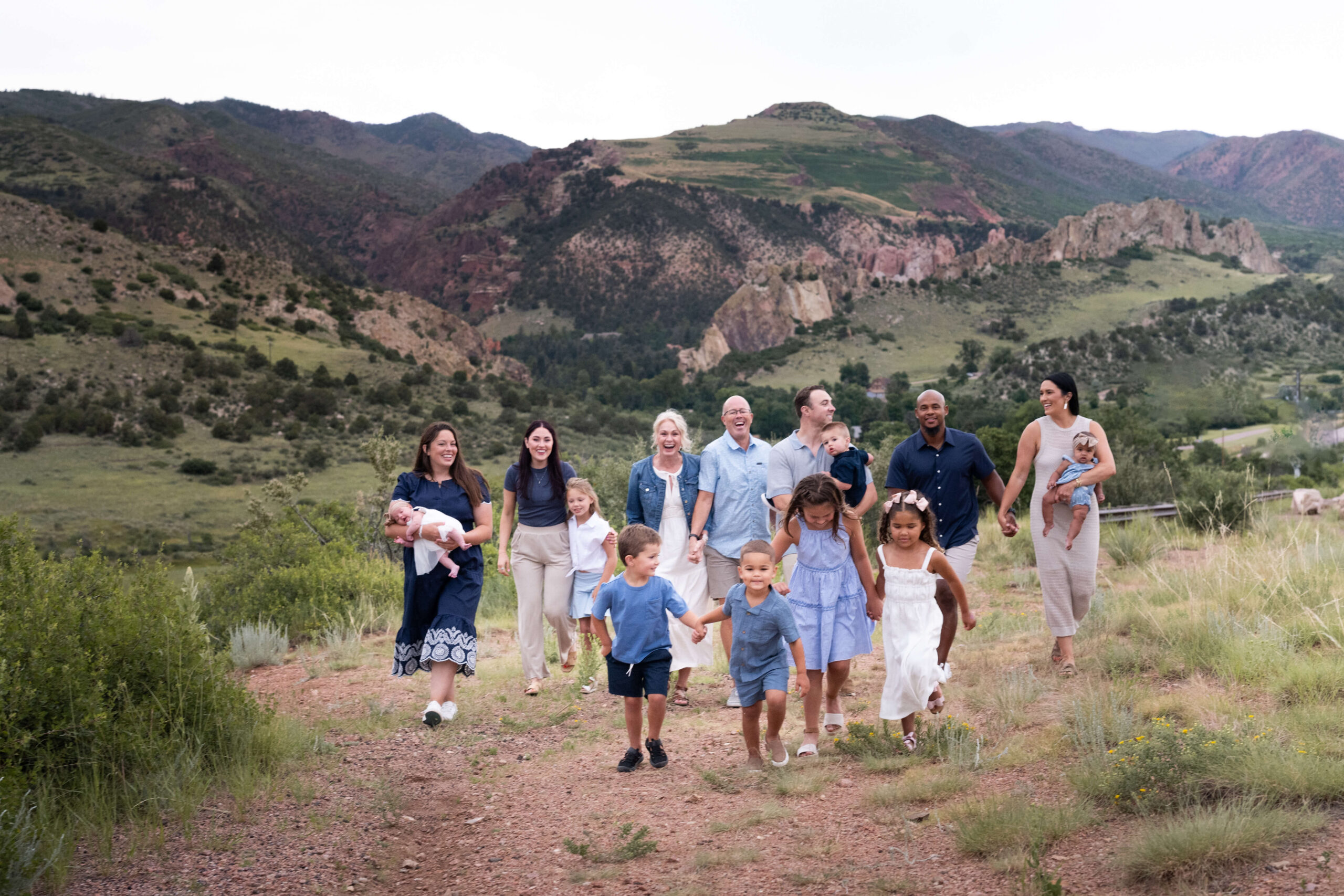 A happy extended family with many toddlers hiking up a hill holding hands