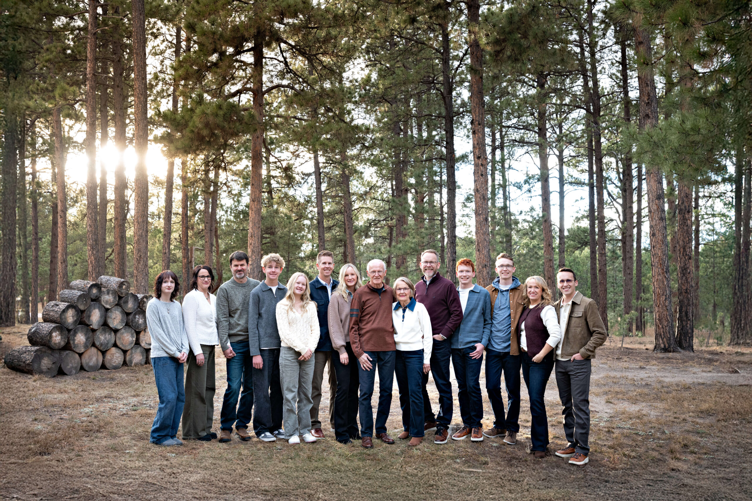 A large extended family stands in a pine forest park at sunset smiling after finding montessori schools in colorado springs