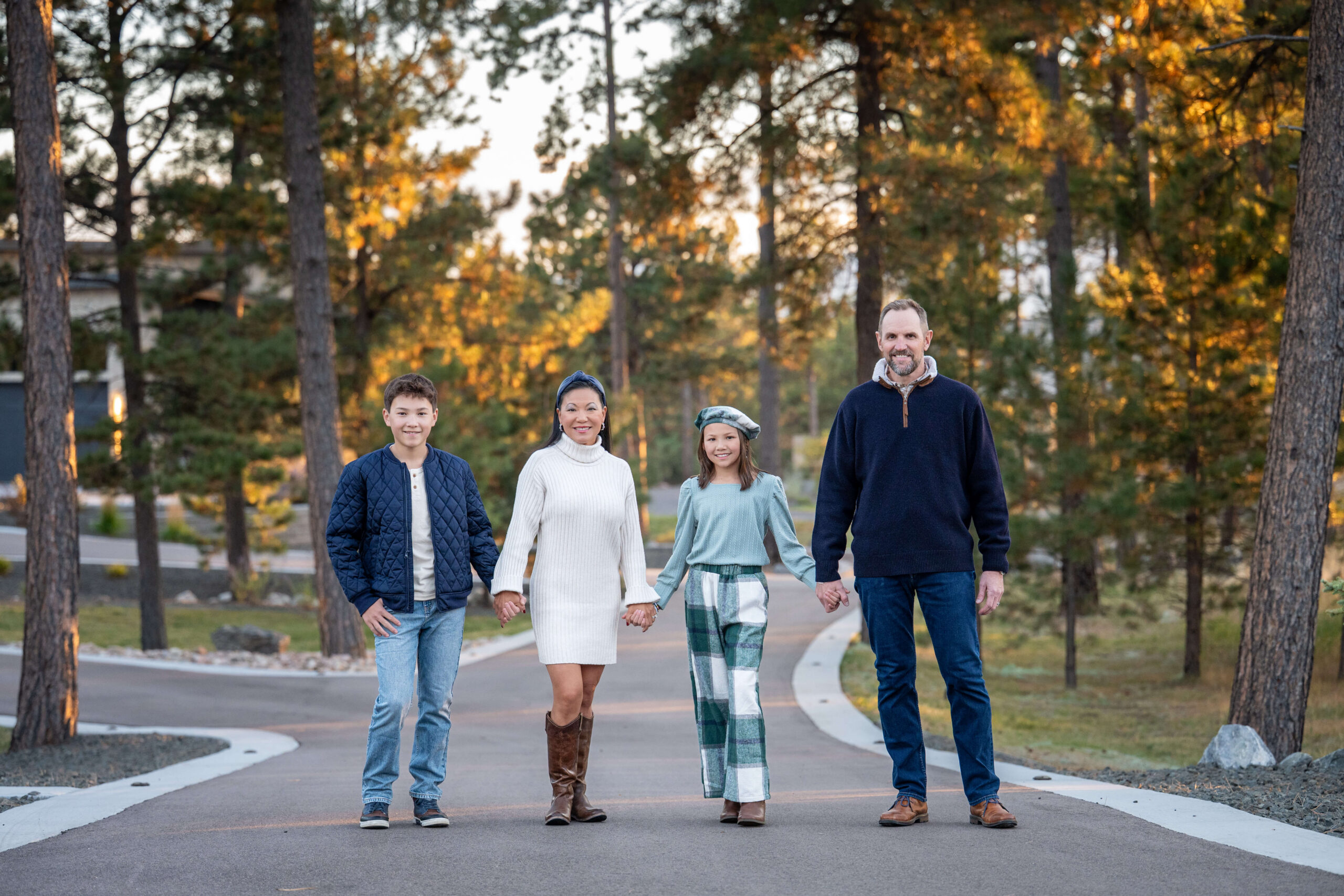 A mom and dad stand smiling in a park sidewalk holding hands at sunset after visiting a pediatric dentistry in colorado springs